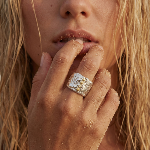Bague Luna Cosmos portée sur les mains dans le sable – bijou artisanal français